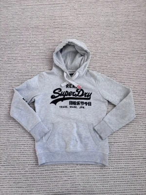 Superdry hoodie Grå - Galet snygg hoodie från Superdry. Mycket bra skick, inga skador. Storlek S. Färg grå. Skriv vid frågor eller funderingar! 😁
