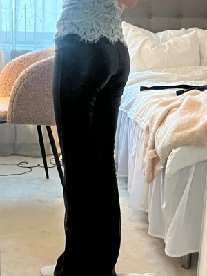  utsvängda skinnbyxor - Säljer ett par svarta skinnbyxor med utsvängda ben och hög midja. Materialet har en glansig finish som ger en trendig look. Perfekta för dig som vill ha ett par byxor som sticker ut och är lätta att styla till olika outfits. (De har hög midja men jag viker ner dom)