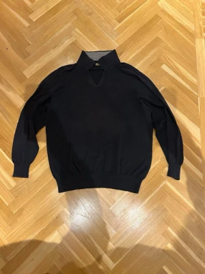 Loro Piana tröja - Stickad Loro piana tröja med klassisk krage och v-ringning. Tröjan har långa ärmar och ribbade muddar vid ärmslut och nederkant. Perfekt för en clean och enkel look.