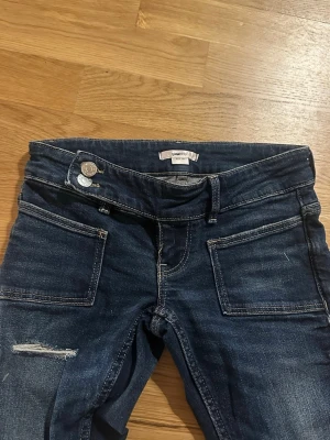 Mörkblå bootcut low waist  jeans Gina Tricot - Säljer ett par mörkblå bootcut jeans från Gina Tricot. Sparsamt använda och inga slitage i botten av jeansen! I storlek xxs tall! 