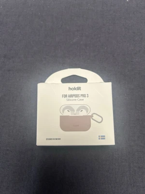 Beige silikonfodral Holdit AirPods Pro 3 - Snyggt beige silikonfodral från Holdit för AirPods Pro 3. Fodralet har en mjuk, matt finish och kommer med en metallkarbinhake så du enkelt kan fästa det på väskan eller nyckelknippan. Perfekt för att skydda dina hörlurar mot repor och stötar. Aldrig använt, helt nyskick då det är fel storlek! Gick tyvärr inte att lämna tillbaka då jag redan hade öppnat förpackningen! Nypris 149 säljer för 105!💗 Skriv ifall ni har någon fundering!