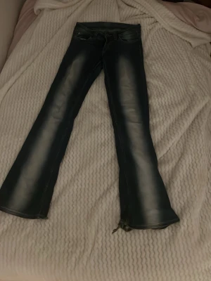 Blå bootcut jeans från Miss Sixty - Säljer ett par blå bootcut jeans från weekday med slitningar och utsvängda ben. Jeansen har klassisk femficksdesign och en snygg tvätt med ljusare partier framtill och baktill. Materialet är denim med en mjuk känsla och cool vintage-look.