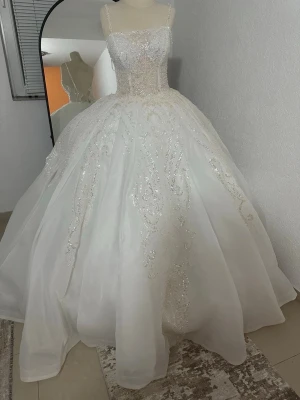 Vit glittrig balklänning - Drömmig vit långklänning med glittriga detaljer och spets upptill. Klänningen har en markerad midja och en stor, voluminös kjol som ger en prinsesskänsla. Perfekt för bröllop