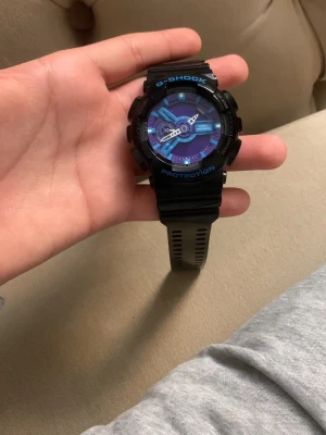 En G-SHOCK KLOCKA  - En fin g-shock i svart,blå och lila färg saknar ba batteri annars den e helt ny.