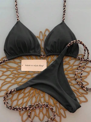 Svart bikini med leoparddetaljer - Trendig svart bikini med trekantsformade kupor och smala band i leopardmönster. Knytmodell både upptill och nedtill för justerbar passform. Perfekt för strandhäng eller poolparty.