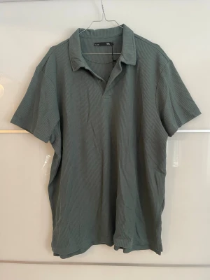 Grön piké i våfflat material -  Snygg salviagrön pikétröja i mjukt, våfflat material. Skön oversized passform och perfekt till både jeans och shorts.