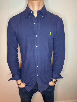  Blå Ralph Lauren skjorta  - Hej! Vi säljer nu denna Ralph Lauren skjortan i storlek M skicket är bra! Men däremot saknas en knapp men går enkelt att fixa för den händiga😉Därav priset 240kr. // studio II Resell 