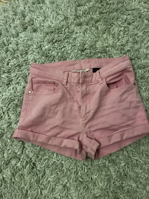 Rosa shorts med uppvikta ben - Snygga rosa shorts med uppvikta ben och klassisk femficksmodell. De har bälteshällor och stängs med knapp och dragkedja. Perfekta för varma dagar och ger en fräsch look till din outfit.