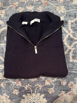 Mörkblå halvziptröja Selected Homme - Mörkblå stickad tröja från Selected Homme med halv dragkedja och hög krage. Tröjan har ribbade muddar vid ärmslut och nederkant, och är gjord i ett grovstickat material som ger en klassisk och stilren look. Storleken är i M/M men passar dig som bär L också👌🏼Rökfritt hem.