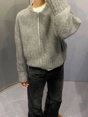 Grå stickad tröja med dragkedja från Zara  - Mysig grå stickad tröja från Zara med halv dragkedja framtill och ribbstickad struktur. Tröjan har avslappnad passform, nedhasade axlar och breda muddar vid ärmslut och nederkant. Perfekt för lager på lager och höstmys. Priset går att diskuteras 🩷 första bilden är lånad för att visa hur den sitter på