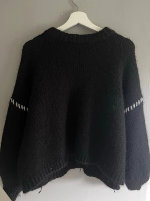 Svart stickad tröja från Vero Moda - Mysig svart stickad tröja från Vero Moda med rund hals och diskreta vita detaljer vid ärmarna. Tröjan har en avslappnad passform och är perfekt för kyliga dagar. Materialet är mjukt och fluffigt, vilket gör den extra skön att bära. Priset går att diskuteras, kolla gärna mina andra annonser för rabatt☺️