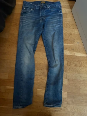Blå slim fit jeans med slitningar - Snygga blå slim fit jeans med lätt slitna detaljer och klassisk femficksdesign. Jeansen har normalhög midja och raka ben. Tillverkade i denim med en tvättad look som ger en avslappnad vibe. Perfekta för en casual stil.