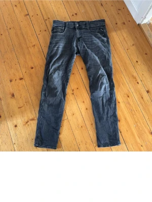 Mörkgrå jeans från Replay - Snygga mörkgrå jeans från Replay med klassisk femficksmodell och raka ben. Jeansen har diskreta slitningar och kontrastsömmar som ger en cool look. Tillverkade i mjukt denimtyg som sitter skönt hela dagen.