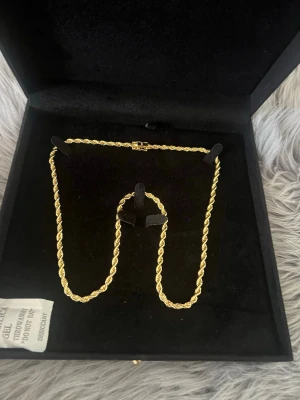 Guld plänterat 18K - Snyggt guldfärgat halsband med tvinnad kedja som ger en exklusiv look. Halsbandet har ett dekorativt lås och levereras i en svart ask. Perfekt för dig som vill ha ett statement-smycke med elegant känsla.