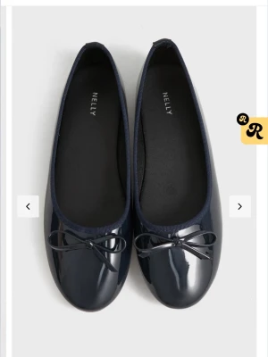 Mörkblå lackballerinaskor från Nelly - Snygga mörkblå ballerinaskor från Nelly i glansigt lackmaterial. Klassisk rund tå och dekorativ rosett framtill. Perfekta att matcha med jeans eller kjol för en trendig look.