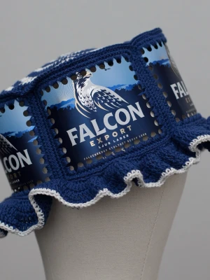 Virkad ölhatt Falcon - Unik virkad ölhatt med Falcon.   Virkad i 100% bomull. Passar upp till ca 60cm.  Vissa burkar kan ha mindre repor eller bucklor, vilket tyvärr kan uppstå under tillverkningen av hattarna. Insidan av burkarna slipas efter hålen tagits för att undvika vassa kanter. Därför kan det ibland finnas lite slipmärken, men det är inget som stör eftersom det är på insidan av hattarna.  Färger kan variera något beroende på skärminställningar.