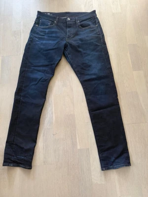Mörkblå G-Star RAW 3301 jeans - Säljer ett par mörkblå jeans från G-Star RAW, modell 3301 Straight Tapered. Klassisk femficksdesign med snygga kontrastsömmar och knappgylf. Perfekta för dig som gillar en rak men avsmalnande passform.