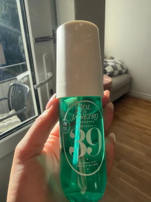Sol de Janeiro 39 Parfymmist - Fräsch parfymmist från Sol de Janeiro med doftnummer 39. Flaskan är grön med vit text och har ett vitt lock. Perfekt att spraya på kroppen för en upplyftande känsla. Flaskan är gjord av plast och har en modern, stilren design.