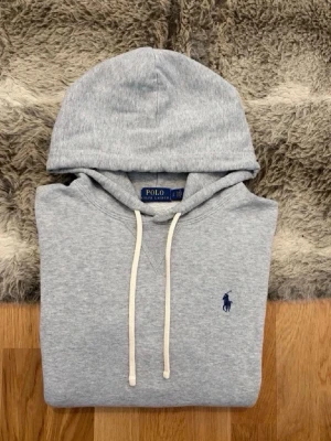 Grå hoodie från Polo Ralph Lauren - Snygg grå hoodie från Polo Ralph Lauren. Tröjan är i perfekt skick och sitter i strl S Hör av er vid funderingar!