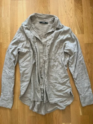 Beige skjorta med knappar från Only - Stilren beige skjorta från Only med klassisk krage och knappar framtill. Skjortan har lång ärm och är tillverkad i ett mjukt bomullsmaterial. Perfekt för en avslappnad men snygg look.