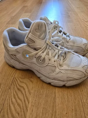 Vita Adidas sneakers med meshdetaljer - Säljer ett par vita Adidas sneakers med chunky sula och meshdetaljer. Skorna har klassisk snörning, Adidas-logga på plösen och en sportig design. Materialet är en mix av mesh och syntet för bra andningsförmåga och komfort.