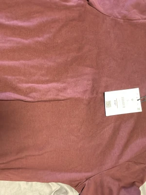 Vinröd t-shirt med kontrastkrage - Säljer en vinröd t-shirt från Bershka med beige kontrastkrage. T-shirten har klassisk passform och är tillverkad i mjuk bomull, perfekt för en avslappnad och trendig look.