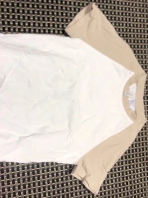 Vit och beige t-shirt från H&M Divided - Säljer en stilren t-shirt från H&M Divided i vitt med beige ärmar och krage. Klassisk modell med korta ärmar och rund hals. Perfekt till jeans eller shorts för en enkel och clean look.