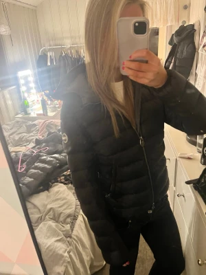 Svart pufferjacka med huva - Säljer min så snygga Colmar jacka, en svart jacka med huva och dragkedja framtill. Grå insida, passar perfekt till senare vinter och våren!💕