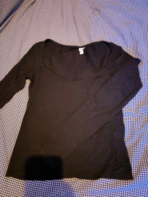 Svart långärmad topp med rund hals - En enkel och stilren svart långärmad topp med rundad halsringning. Tillverkad i mjukt bomullsmatrial. Perfekt att matcha med jeans eller kjol.