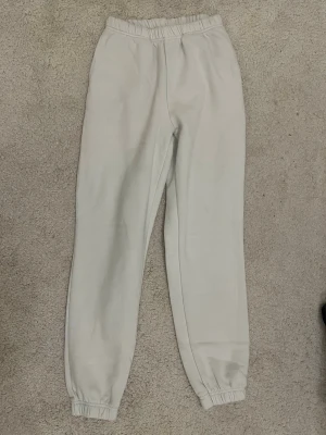Vita mjukisbyxor med resår - Säljer ett par klassiska vita mjukisbyxor med resår i midjan och vid bensluten. Perfekta för chill dagar hemma eller när du vill ha det extra bekvämt. Tillverkade i mjukt bomullsmaterial för skön känsla hela dagen.