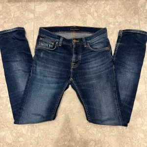 nudie jeans - storlek 28/32 passar 29/32 Säljer ett par mörkblå slim fit jeans från Nudie Jeans med klassiska fem fickor och snygga kontrastsömmar. Jeansen har en lätt tvättad look och är tillverkade i mjuk denim med stretch för extra komfort. Perfekta till en avslappnad stil.
