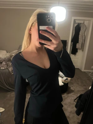 Svart långärmad v-ringad topp - En stilren svart långärmad topp med v-ringning. Toppen har en figurnära passform och är perfekt att matcha med både jeans och kjol. Enkel och klassisk design som passar till många olika looks.den sitter som storlek S inte alls M