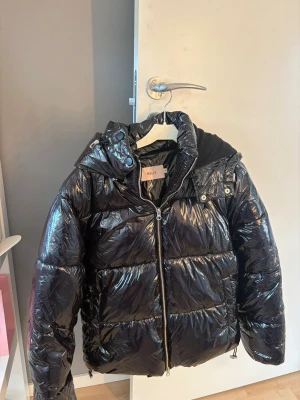 Svart pufferjacka från Nelly - Snygg svart pufferjacka från Nelly med glans. Den passar även XS