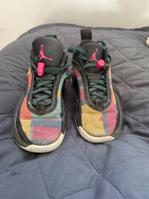 Färgglada Air Jordan sneakers - Säljer ett par Air Jordan sneakers med färgglad mesh i gult, rött, blått och svart. Skorna har svarta detaljer, gröna skosnören och rosa Jumpman-logga på plösen. Snygg och unik design med robust sula och dragflik bak.