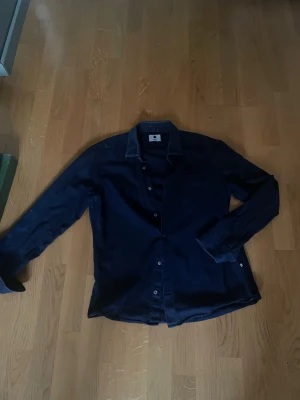 Mörkblå overshirt från NN07 - Snygg mörkblå overshirt från NN07 med klassisk krage och knäppning framtill. Skjortan har långa ärmar och är tillverkad i mjuk bomull som känns skön mot huden. Perfekt för dig som gillar stilrena och tidlösa plagg.