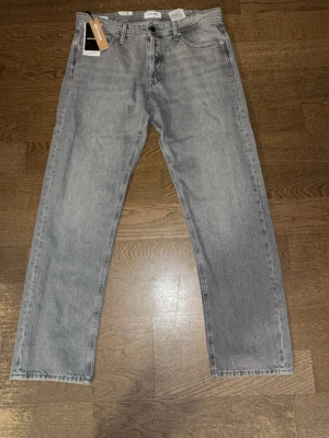 Helt nya Ljusgrå raka jeans från Weekday - Säljer ett par stiliga ljusgråa jeans från Jack & Jones med rak passform och klassisk femficksdesign. Jeansen har normal midja och är tillverkade i bomull. Perfekta för en avslappnad och trendig look. Modellen är relaxed.