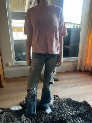 Ljusrosa fluffig topp med kort ärm - Mysig ljusrosa topp med korta ärmar och rund hals. Toppen har en lös passform och är gjord i ett fluffigt material som ger en soft och trendig look. Perfekt att styla med jeans eller kjol för en avslappnad vibe.