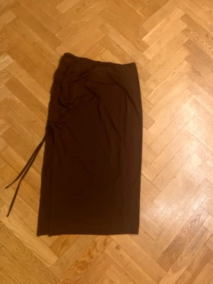 Brun långkjol med snörning - Säljer en brun långkjol med snörning i sidan. Kjolen har en rak passform och är enkel att styla till olika looks. Perfekt för dig som gillar jordnära färger och vill ha en stilren kjol i garderoben. Skriv gärna för mått! 💕