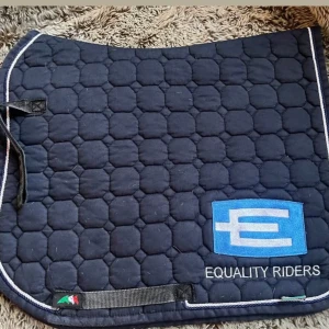 Marinblått schabrak Equality Riders - Säljer ett marinblått schabrak från Equality Riders med vit kant och quiltat mönster. Schabraket har en broderad logga i blått och vitt samt texten 'EQUALITY RIDERS' på sidan. Perfekt till hästutrustningen. Pris diskuteras 