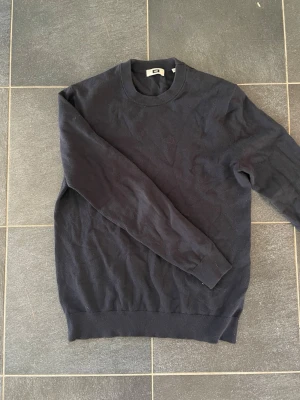 Mörkblå stickad tröja från We fashion - Mörkblå stickad tröja från We fashion i storlek S med rund halsringning och ribbade muddar vid ärmslut och nederkant. Enkel och stilren design som passar till det mesta. Bra skick! Perfekt basplagg för våren! Pris kan diskuteras. 
