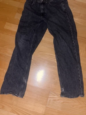 Svarta raka jeans, lite slitna i botten men annars fantastiska! - Ett par svarta jeans med rak passform och klassisk femficksdesign. Jeansen har normal midja och är tillverkade i ett robust denimtyg. Perfekta för en avslappnad och trendig stil.