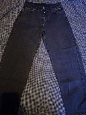 Svarta jeans från Sweet Sktbs - Säljer ett par svarta raka jeans från Sweet Sktbs med broderad logga vid fickan. Jeansen har klassisk femficksdesign, knappgylf och är tillverkade i kraftig denim. Perfekta för dig som gillar streetwear och en avslappnad look.