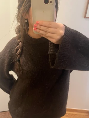 Brun mohair tröja - Mysig mörkbrun stickad tröja med oversized passform och breda ärmar. Tröjan har rund halsringning och är gjord i ett fluffigt, mjukt material som känns lyxigt. Perfekt för lager på lager och chill dagar.