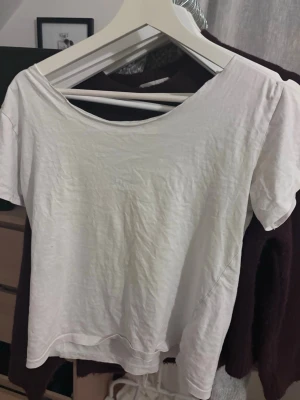 Vit basic t-shirt med rund hals - En enkel vit t-shirt med rund halsringning och korta ärmar. Tillverkad i mjukt bomullstyg som känns skönt mot huden. Perfekt att matcha med jeans eller shorts för en clean och avslappnad look.