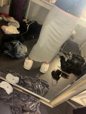 Ljusgrå lång kjol i mjukt material - Säljer en ljusgrå långkjol med rak passform och resår i midjan. Kjolen är gjord i ett mjukt, stretchigt material som sitter bekvämt och följer kroppen. Perfekt för en avslappnad och stilren look.