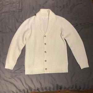 Lindbergh stickad cardigan - Ribbstickad cardigan från lindbergh white. Nedvikt krage med femknappars-stängning med knappar i havannastil. Riktigt skönt material och sitter bra.