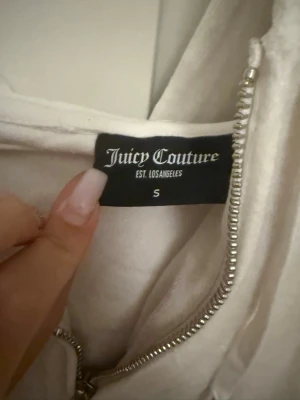 Vit Juicy Couture kofta - Super fin vit kofta från juicy couture. J:et på dragkedjan är lite sönder så det är lite svårare att dra upp dragkedjan, men inte något större problem. 