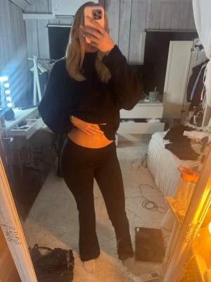 Svarta yoga pants - Säljer ett par svarta leggings med bootcut-modell och hög midja. Stretchigt material som sitter tajt över låren och släpper ut nedtill. Perfekta för en trendig och bekväm look. Inga synliga detaljer eller loggor.