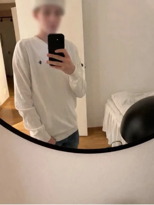 Vit tröja från Morris Stockholm XS - Säljer en stilren vit tröja från Morris Stockholm i storlek XS. Tröjan har rund halsringning, långa ärmar och en liten broderad logga framtill. Perfekt för en clean och klassisk look.