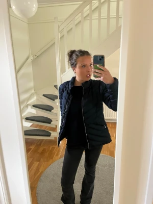 Svart pufferjacka med dragkedja - Säljer en svart pufferjacka med snygg quiltad design och dragkedja framtill. Jackan har en klassisk passform och är perfekt för kalla vinterdagar. Materialet är syntet och jackan har en enkel, stilren look som passar till många outfits.